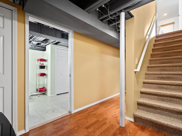 staircase featuring baseboards, wood finished floors, and recessed lighting