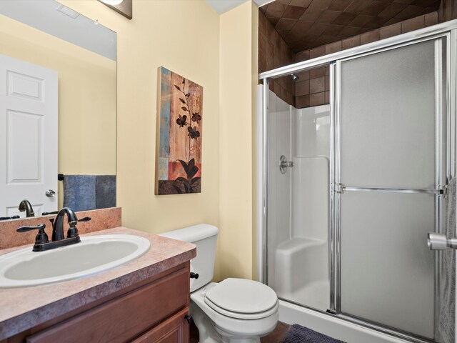 full bathroom featuring toilet, vanity, and a stall shower