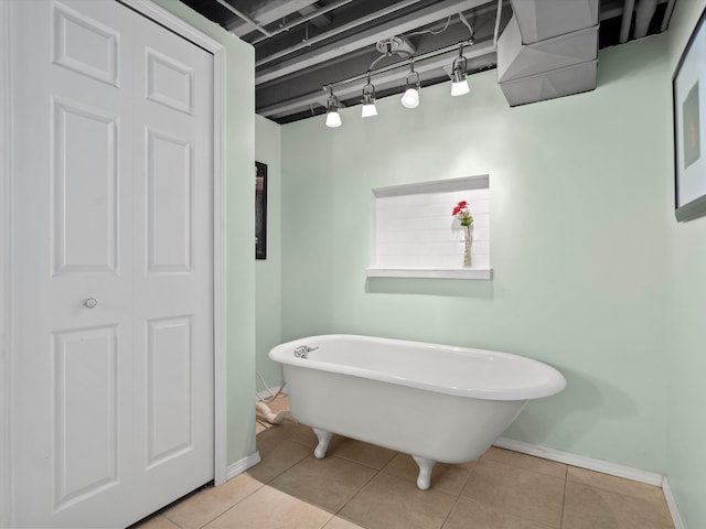 bathroom with a freestanding bath, rail lighting, tile patterned flooring, and baseboards