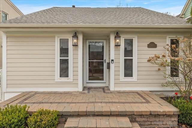 doorway to property with a shingled roof