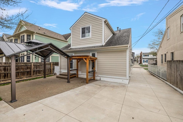 back of house featuring a patio, a shingled roof, and fence