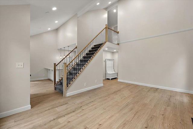 stairs featuring a towering ceiling, wood finished floors, recessed lighting, and baseboards