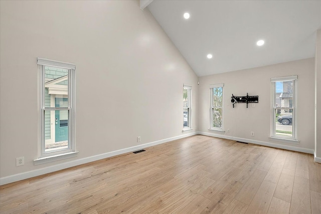 unfurnished room with baseboards, visible vents, plenty of natural light, and high vaulted ceiling