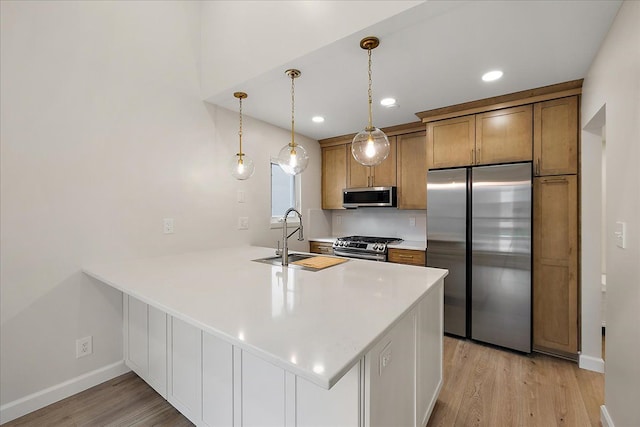 kitchen featuring a sink, stainless steel appliances, baseboards, light wood-type flooring, and a peninsula