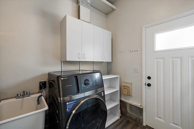 clothes washing area with dark wood-style floors, a sink, cabinet space, and washer / clothes dryer