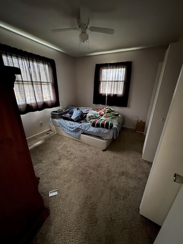 carpeted bedroom featuring multiple windows and a ceiling fan