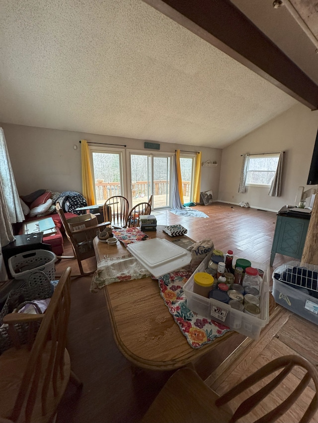 living room featuring vaulted ceiling with beams, a textured ceiling, and wood finished floors