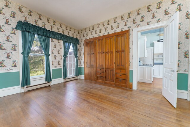 11811 Laird Rd, Brooklyn, MI 49230 - spare room featuring light wood-style floors, baseboard heating, wallpapered walls, and baseboards