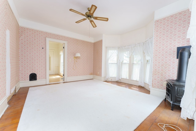 11811 Laird Rd, Brooklyn, MI 49230 - unfurnished living room with a wood stove, ceiling fan, wallpapered walls, and light wood-type flooring