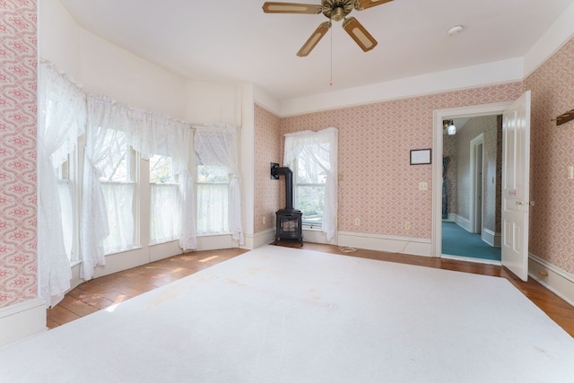 11811 Laird Rd, Brooklyn, MI 49230 - interior space featuring a wood stove, ceiling fan, wallpapered walls, and wood finished floors