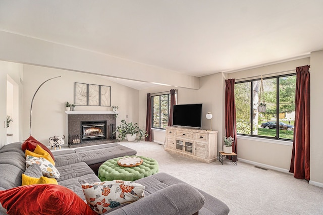 living room featuring a glass covered fireplace, visible vents, carpet flooring, and baseboards