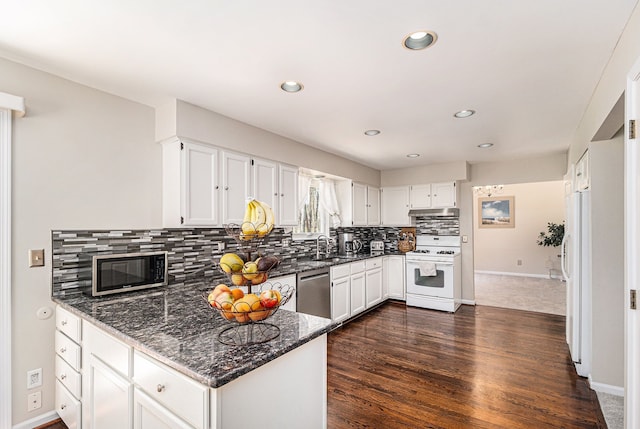 kitchen with dark stone counters, decorative backsplash, appliances with stainless steel finishes, under cabinet range hood, and baseboards
