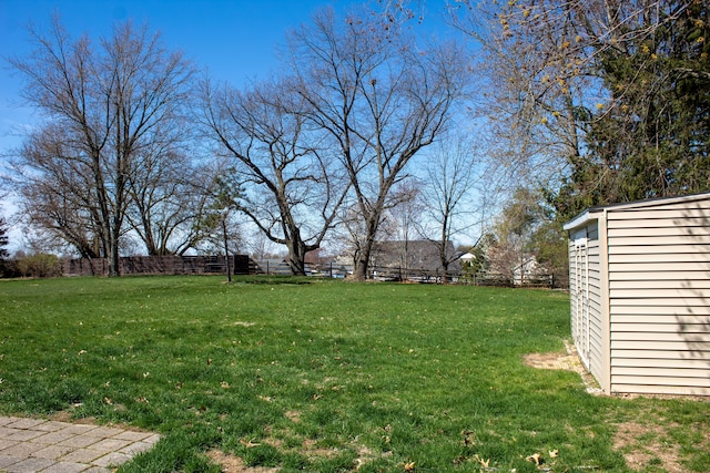 view of yard featuring fence, a storage unit, and an outdoor structure