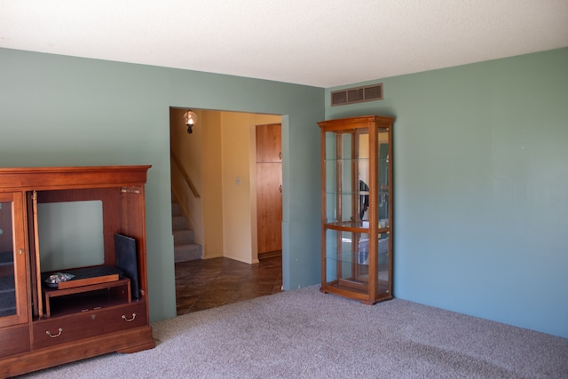 unfurnished living room featuring stairs, carpet flooring, and visible vents