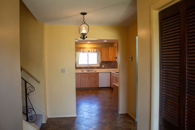 kitchen featuring dishwasher, baseboards, light countertops, a sink, and backsplash