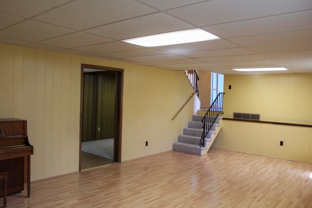 basement featuring stairway, a paneled ceiling, wood finished floors, and visible vents