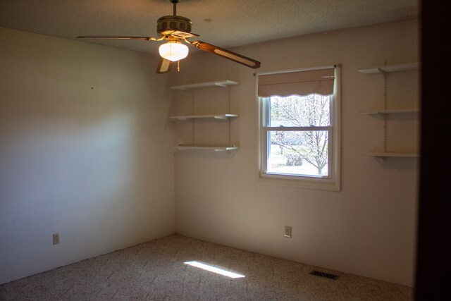 empty room featuring carpet, a ceiling fan, and visible vents