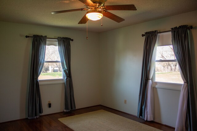 empty room featuring a ceiling fan, dark wood-style floors, and a textured ceiling
