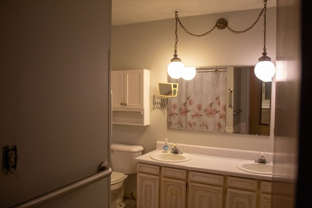 bathroom with double vanity, a sink, and toilet