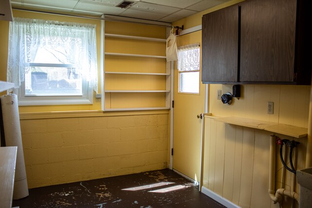 unfurnished dining area with concrete block wall and a paneled ceiling