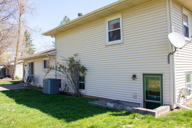 back of property featuring central air condition unit and a yard