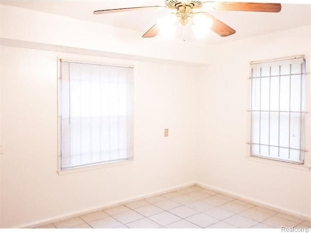 spare room featuring ceiling fan, baseboards, and light tile patterned floors