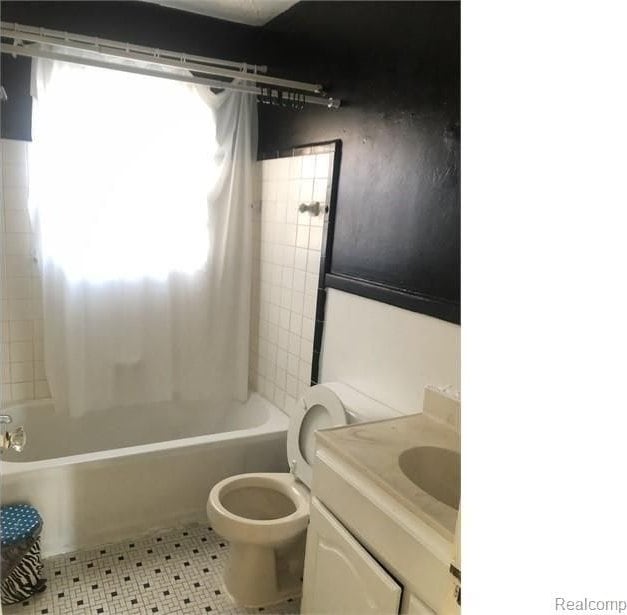 full bath with toilet, vanity, and shower / tub combo with curtain