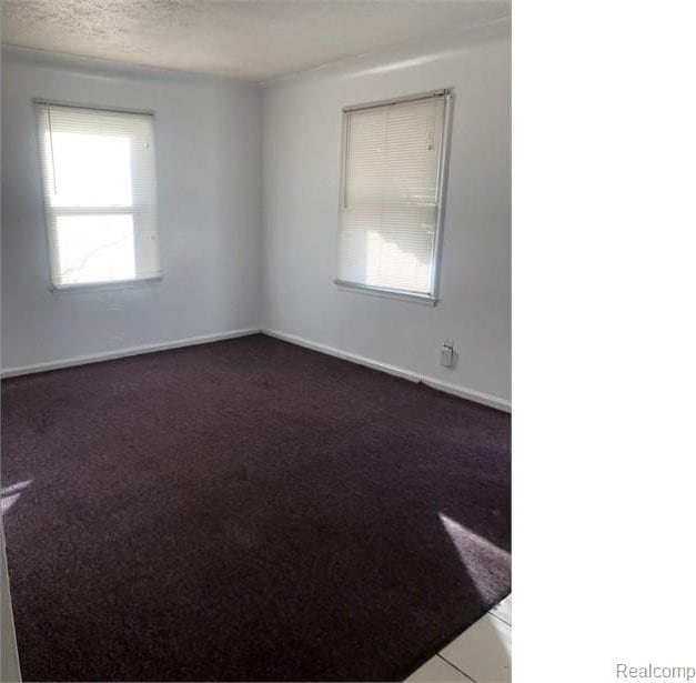 carpeted empty room featuring baseboards and a textured ceiling