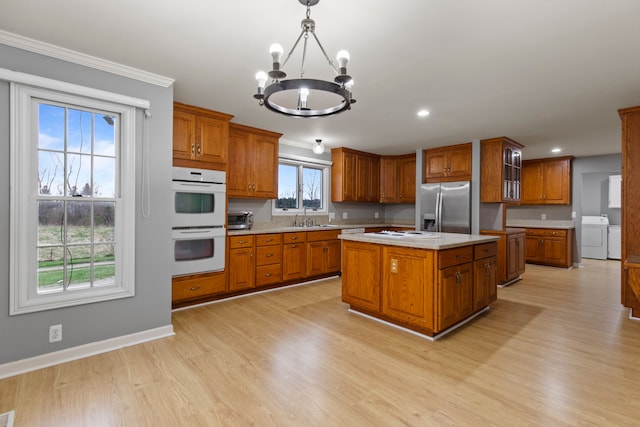 5580 Hegel Rd, Goodrich, MI 48438 - kitchen with a sink, brown cabinetry, washer and clothes dryer, white appliances, and a chandelier