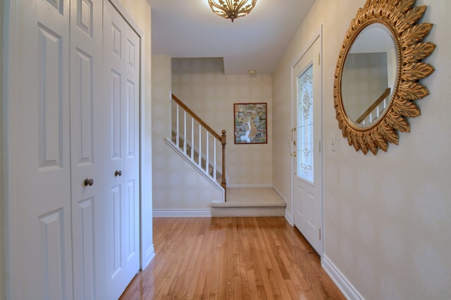 foyer entrance with baseboards, stairs, and light wood-type flooring