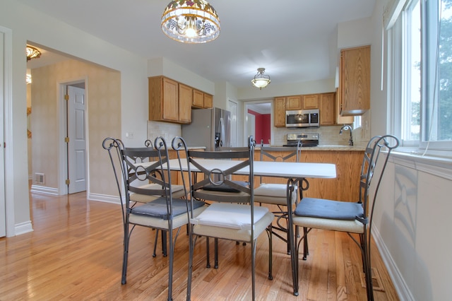 dining room with visible vents, light wood finished floors, baseboards, and an inviting chandelier