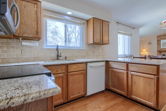 kitchen with white dishwasher, a healthy amount of sunlight, stainless steel microwave, and a peninsula