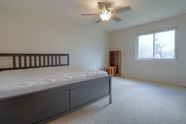 bedroom featuring light colored carpet, baseboards, and a ceiling fan