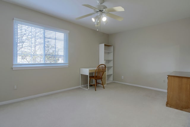 carpeted office space with a ceiling fan and baseboards