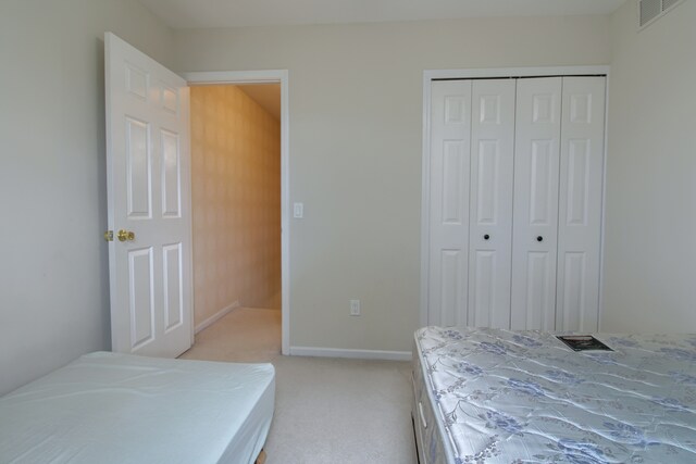 bedroom featuring visible vents, baseboards, a closet, and light colored carpet
