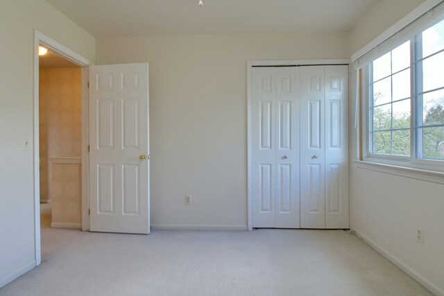 unfurnished bedroom featuring baseboards, carpet flooring, and a closet