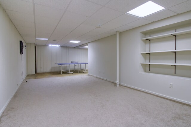 finished basement with baseboards, carpet flooring, and a drop ceiling