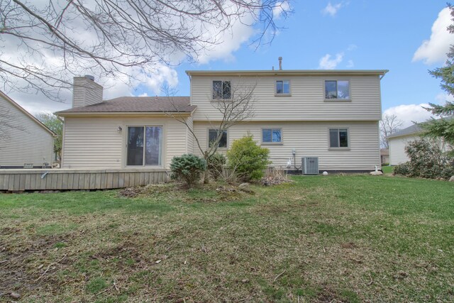back of house with a lawn, central AC, and a chimney