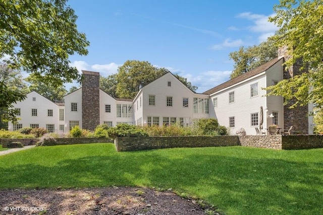 rear view of house with a chimney and a yard