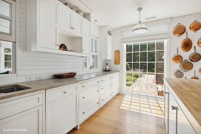 kitchen featuring open shelves, light wood-style flooring, white cabinetry, and a healthy amount of sunlight