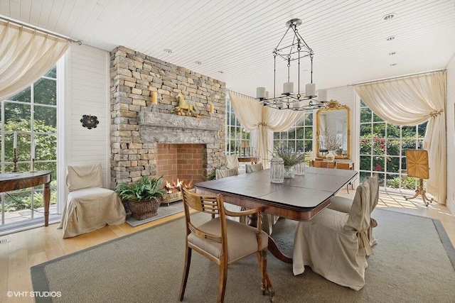 dining space with wooden ceiling, wood finished floors, an inviting chandelier, and a fireplace
