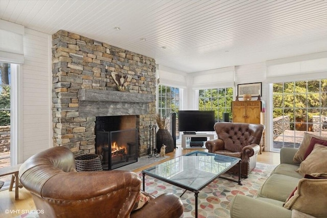 living area with wood finished floors and a stone fireplace