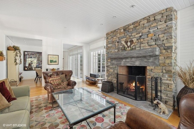 living room with wood finished floors and a stone fireplace