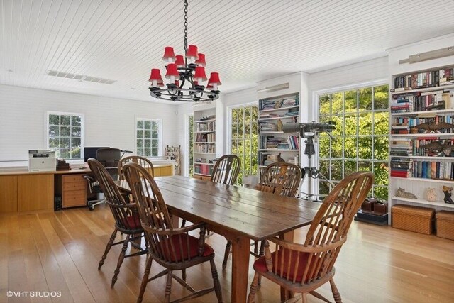 dining area with visible vents, light wood finished floors, wood ceiling, and a notable chandelier