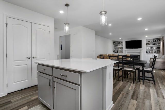 kitchen featuring a fireplace, a center island, dark wood-type flooring, gray cabinetry, and pendant lighting