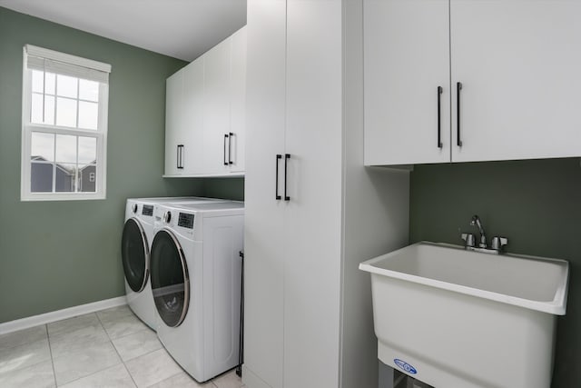 washroom featuring cabinet space, baseboards, washing machine and dryer, and a sink