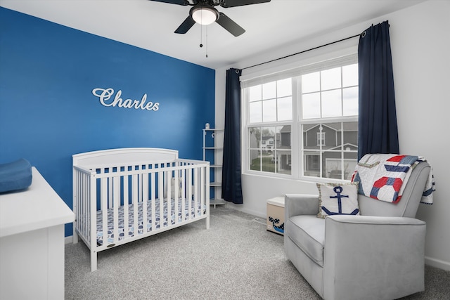 carpeted bedroom featuring baseboards, a ceiling fan, and a nursery area