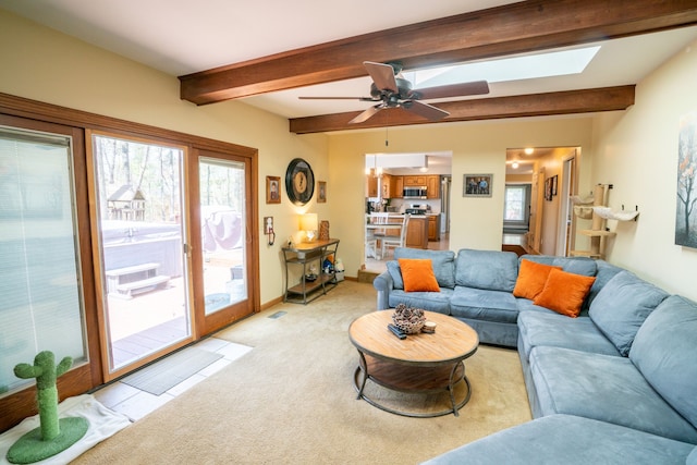 living room with beam ceiling, a skylight, light carpet, and plenty of natural light