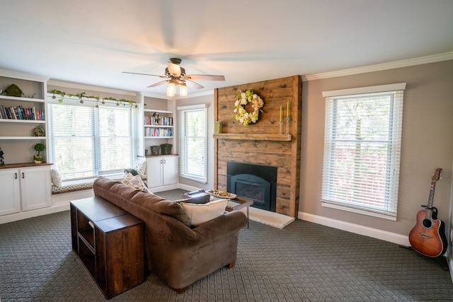 living room featuring dark colored carpet, a ceiling fan, ornamental molding, and a stone fireplace