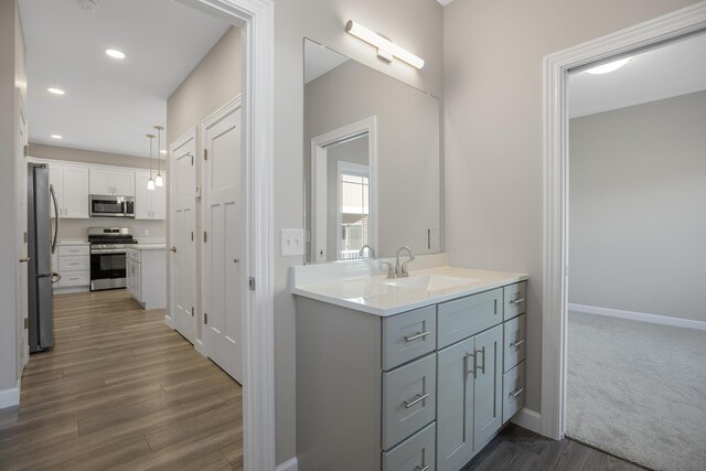 bathroom featuring recessed lighting, wood finished floors, vanity, and baseboards